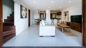 A modern living room with a sofa, dining table, and kitchen area. - Morena Casa & Hotel (Trancoso)