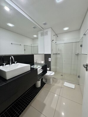 A modern bathroom with a large sink, toilet, and glass-enclosed shower. - Gontijo Inn Hotel (Itajuba)