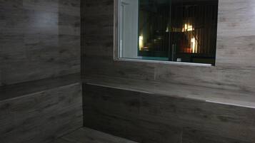 A room with dark wooden paneling and a window with a view of a lit interior.