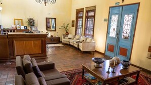 Un vestíbulo amplio con mostrador de recepción, sofás, una mesa de centro y una puerta azul.