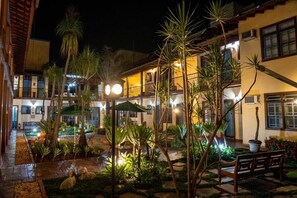 Un patio con piscina, palmeras y un banco.