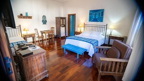 Un dormitorio con cama, escritorio, silla, armario y una pequeña mesa con lámpara.