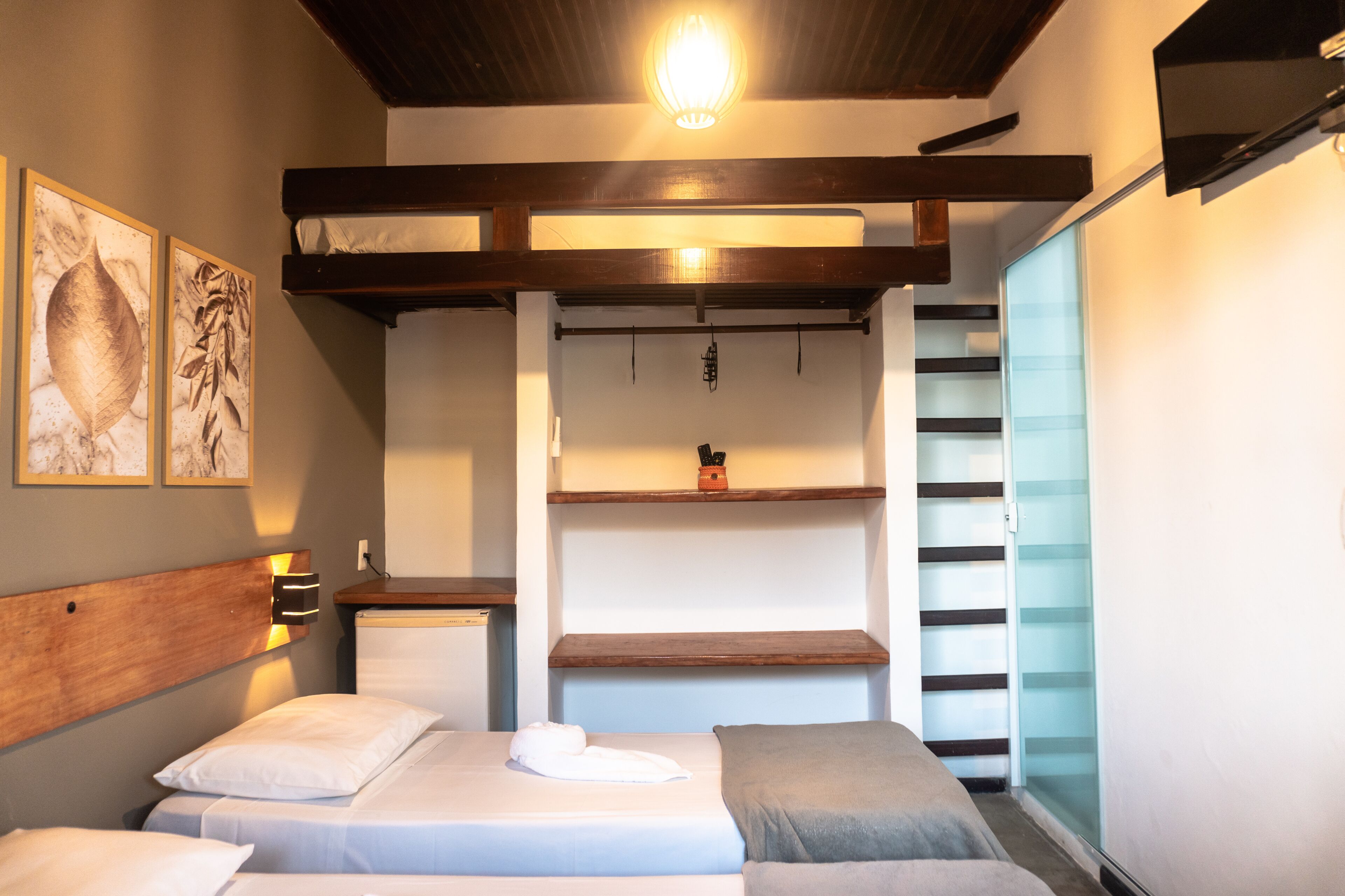 Un dormitorio moderno con literas, vigas de madera, un estante con un adorno y un ventanal de vidrio que da a un balcón.