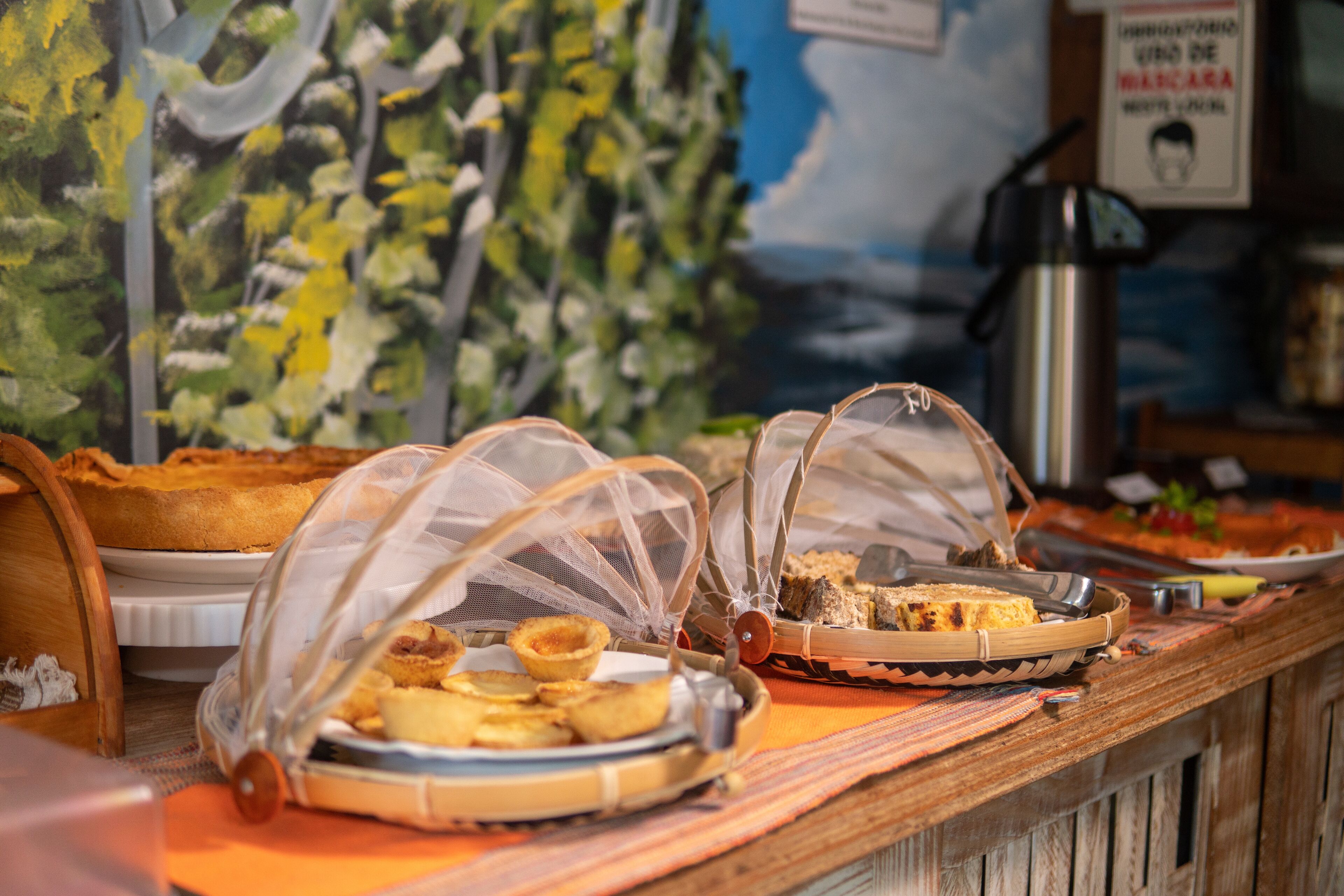 A buffet with various food items covered with protective netting.