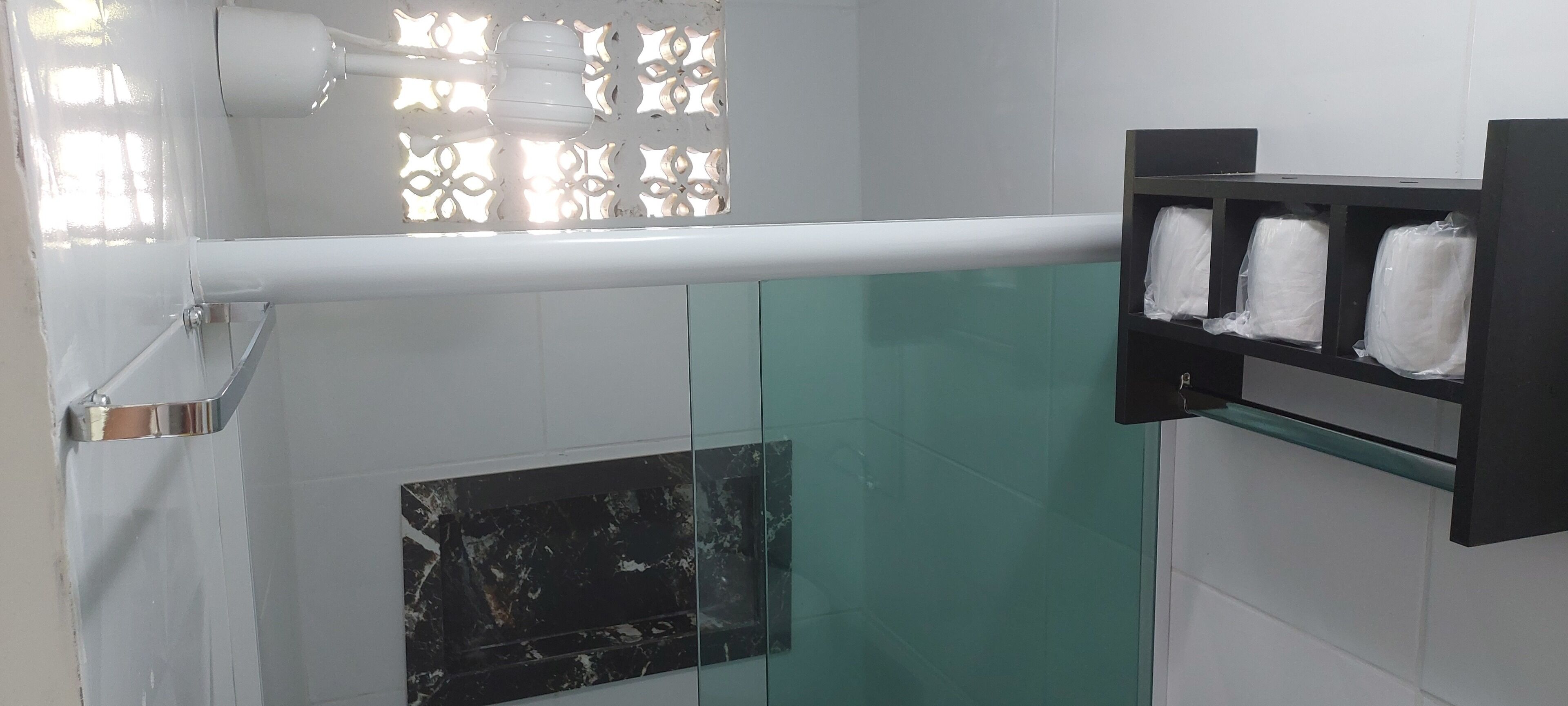 A bathroom with a glass partition, a marble sink, and a towel rack with towels.