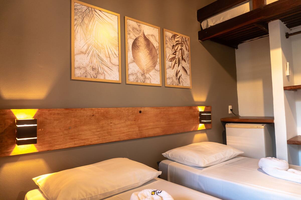 A hotel room with two beds, wooden headboards, and wall-mounted artwork.