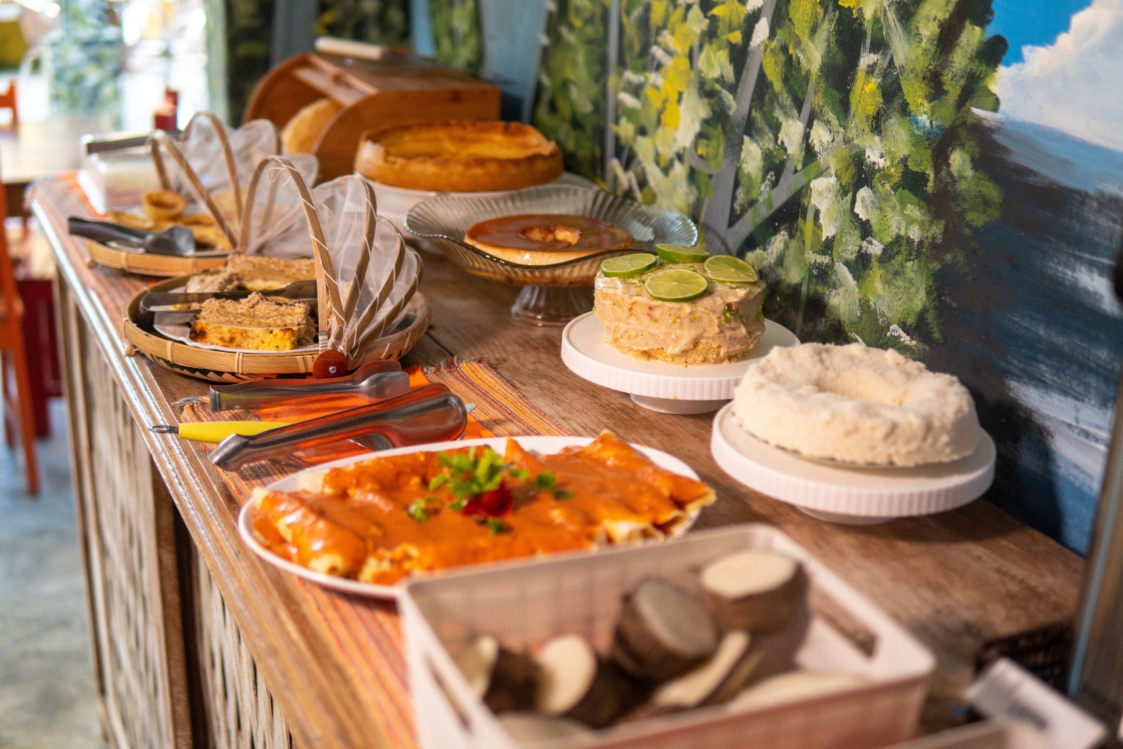 Un bufé con diversos platos, incluyendo un pastel con rodajas de lima, un plato de enchiladas y una variedad de otros alimentos.