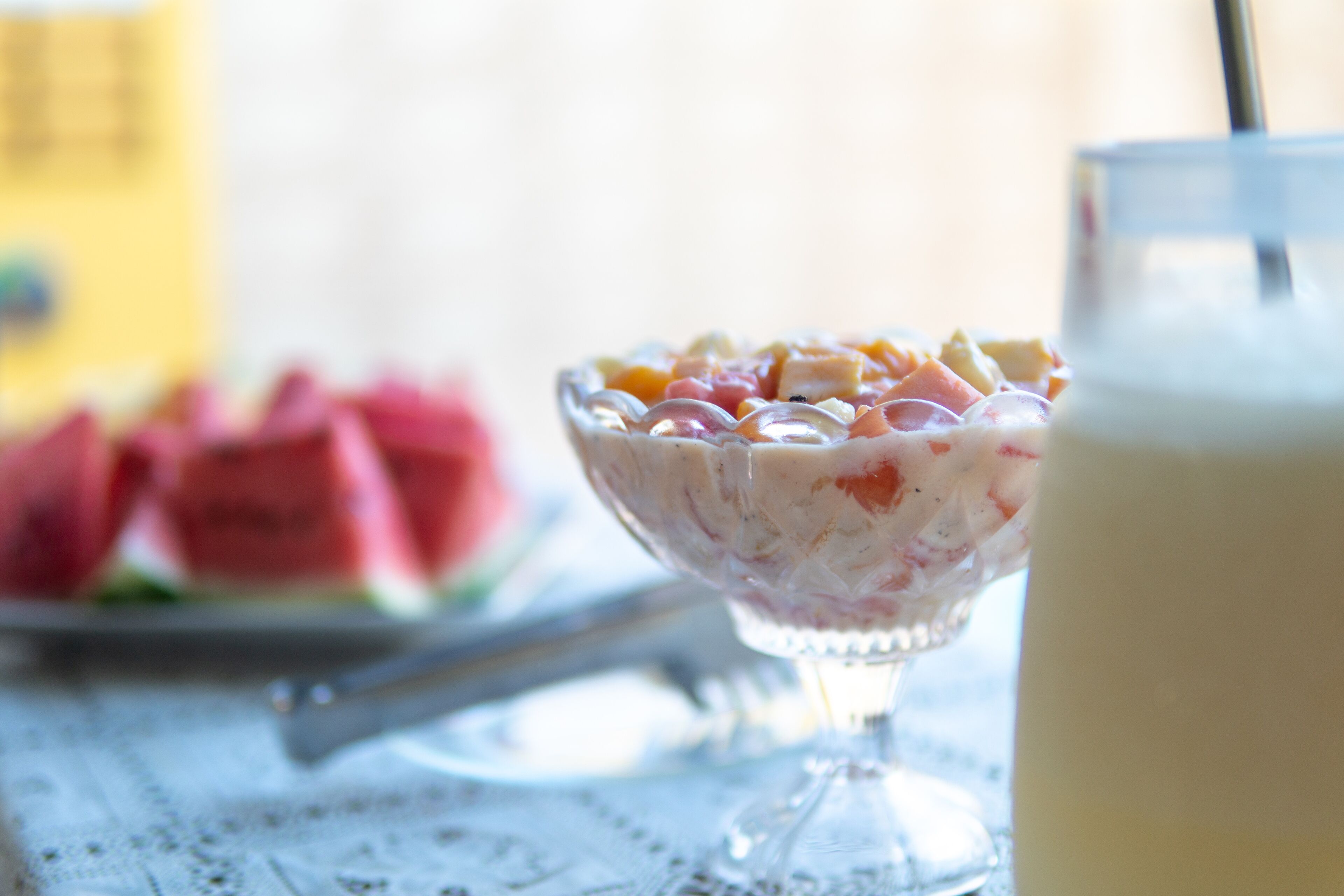 A bowl of fruit salad and a glass of milk on a table.