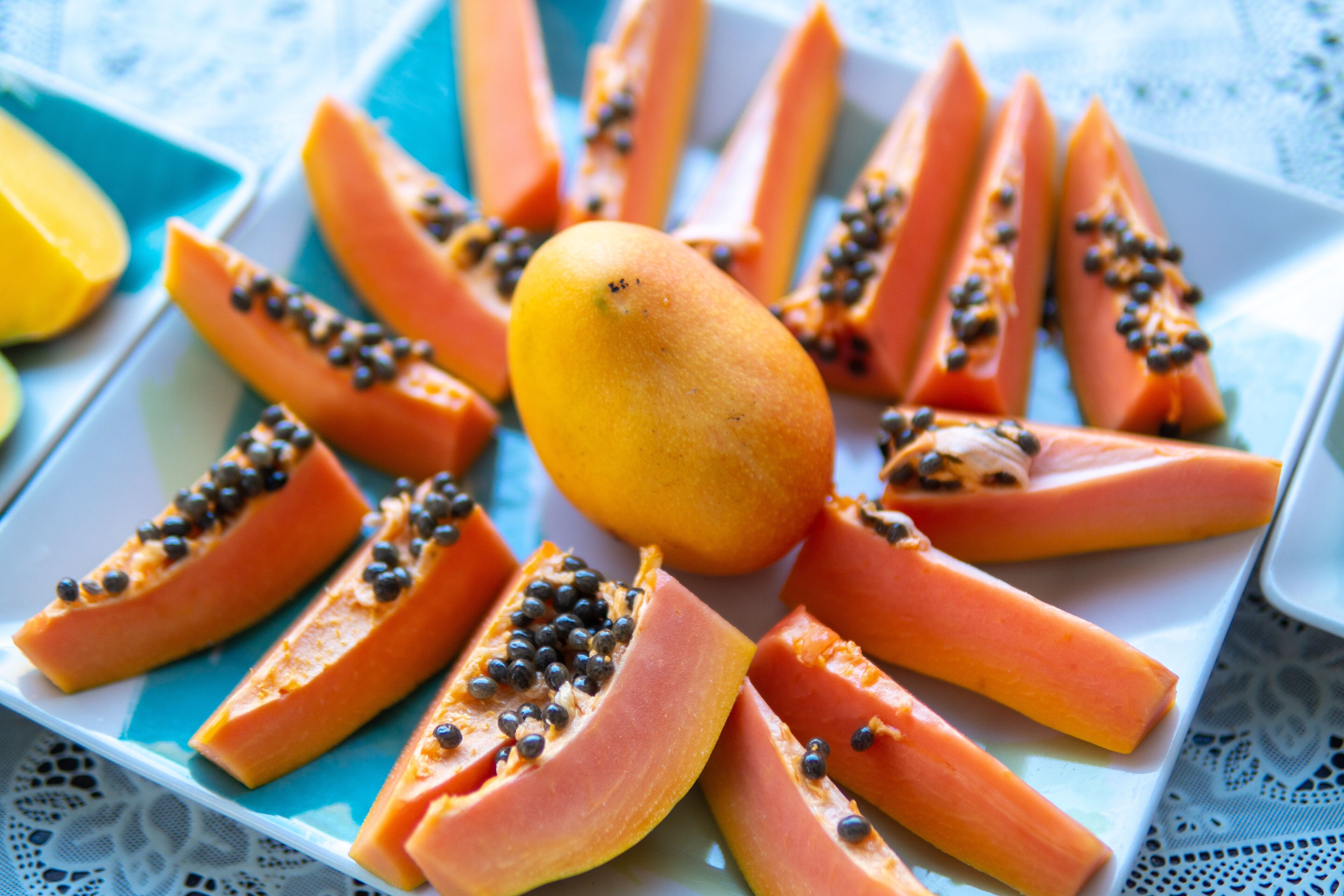 A plate of sliced papaya with black seeds on a blue plate.