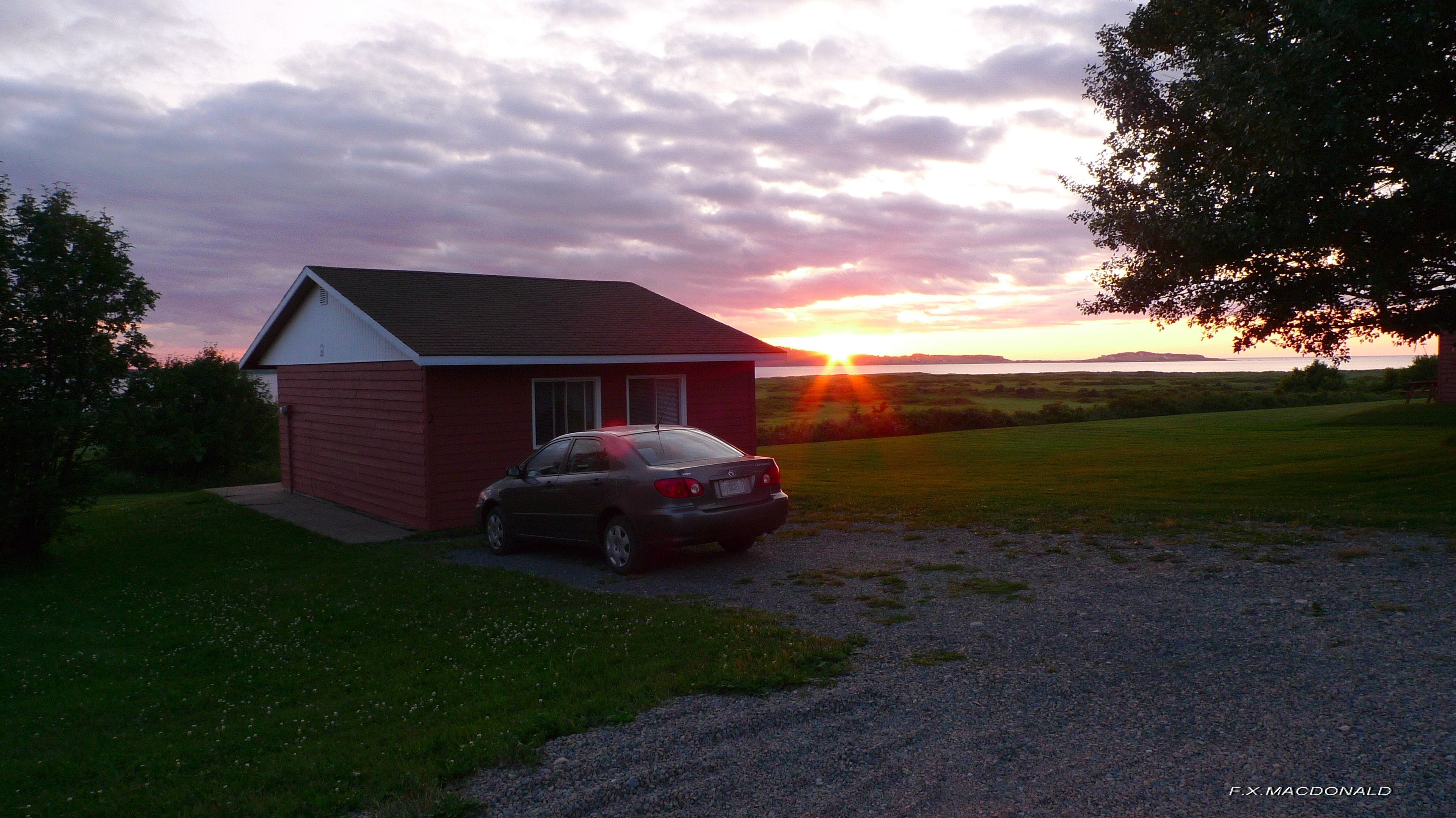 A small red house with a car parked in front.