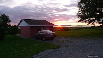 A small red house with a car parked in front.
