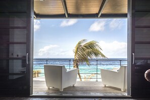 A room with a view of the ocean, two white chairs, and a palm tree. - Pietermaai Ocean Front (Willemstad)