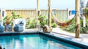 A pool area with lounge chairs, a hammock, and a wooden fence. - Pietermaai Ocean Front (Willemstad)