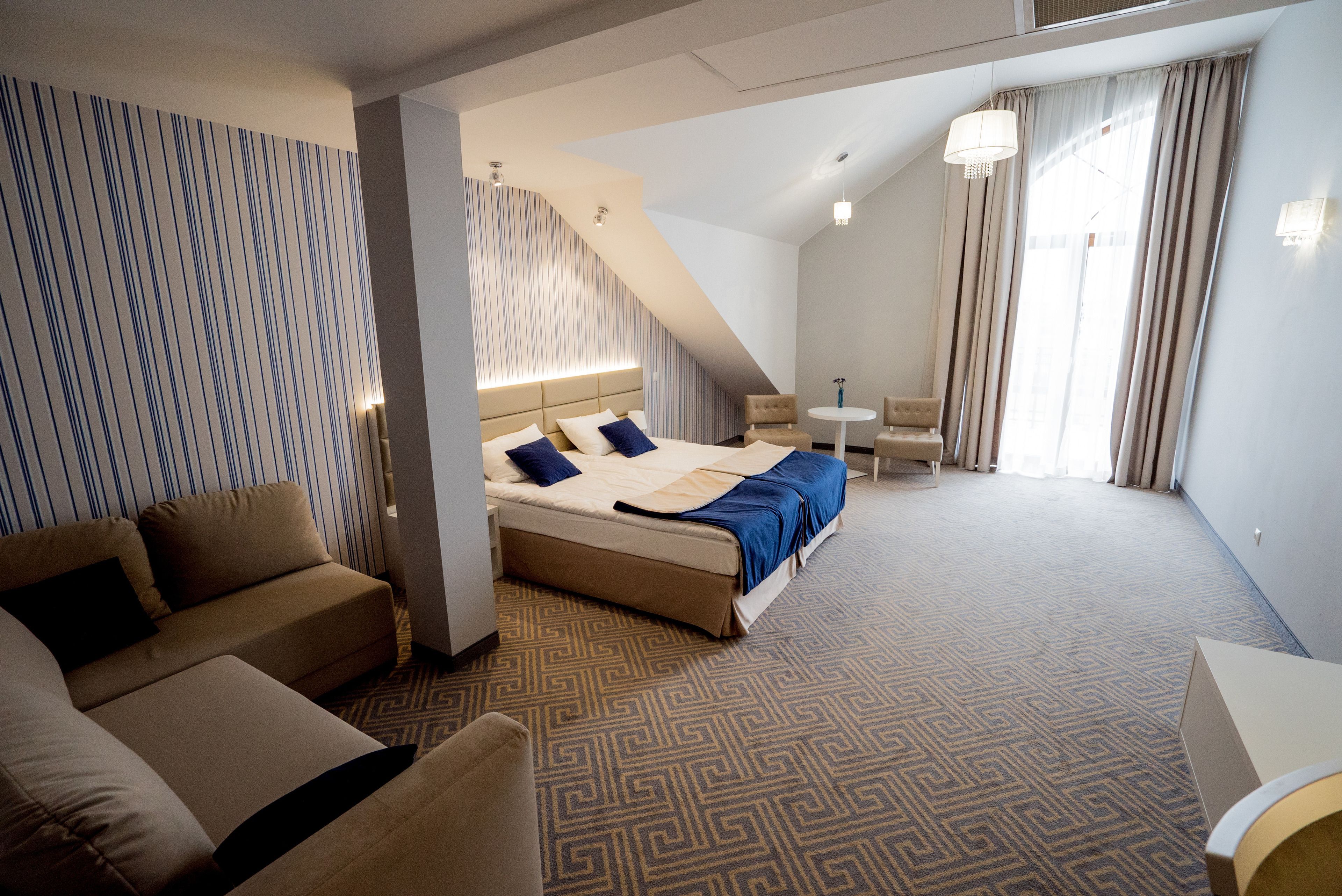 A hotel room with a bed, a sofa, a small table, and a chair.