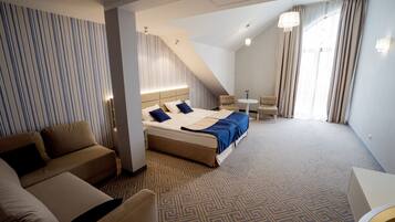 A hotel room with a bed, a sofa, a small table, and a chair.