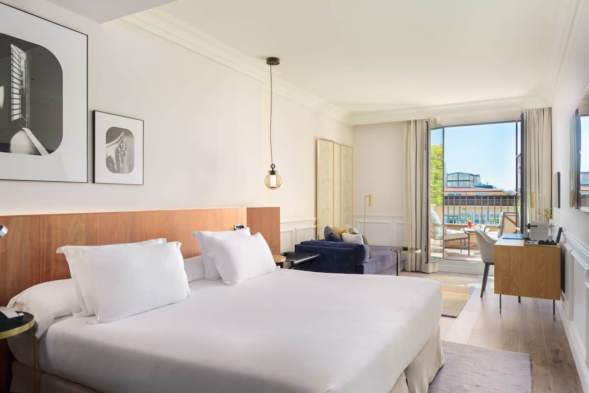 A hotel room with a large bed, a desk, and a view of the city.