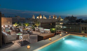 A rooftop terrace with outdoor seating, a pool, and a cityscape view at dusk. - H10 Casa Mimosa (Barcelona)