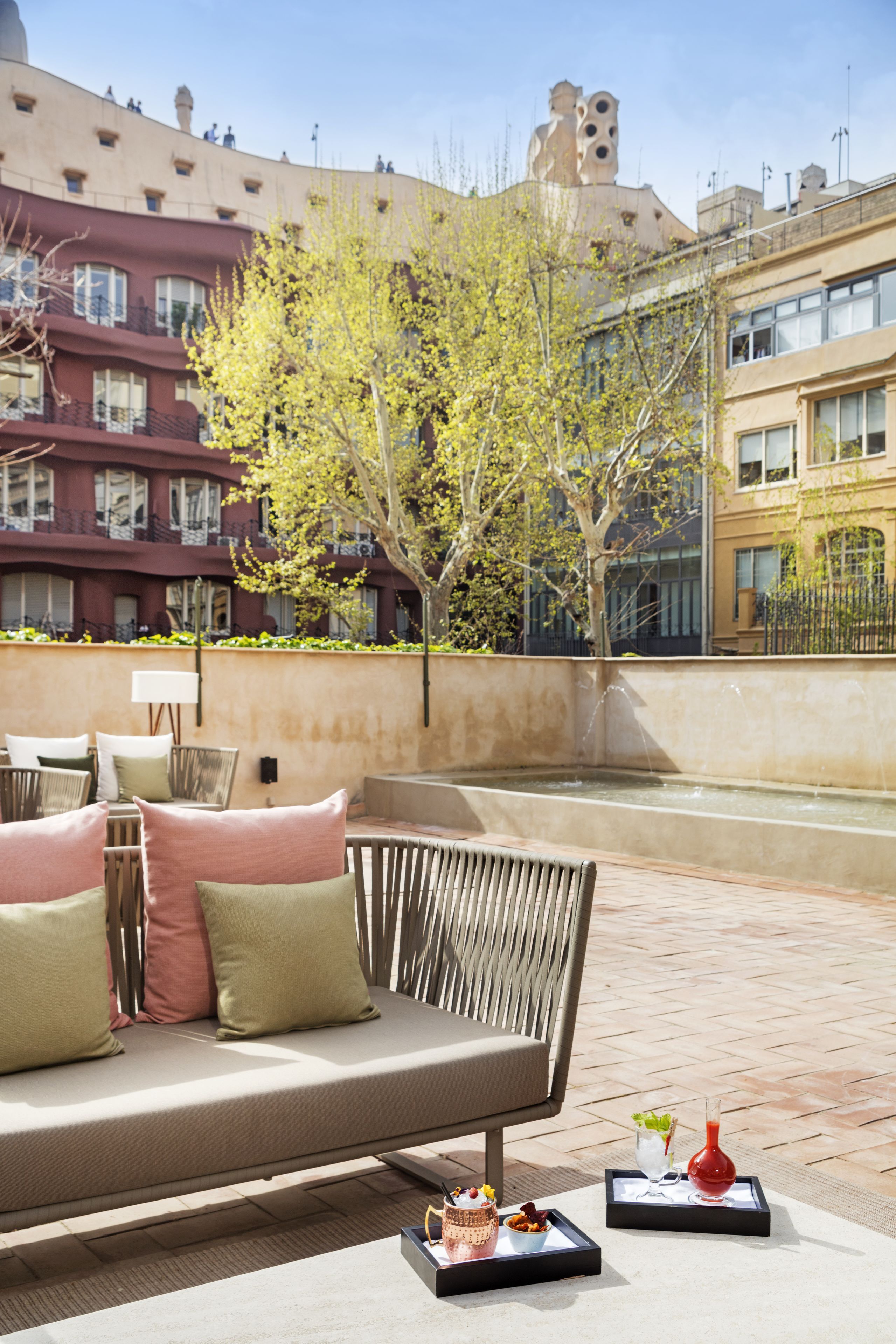 An outdoor seating area with a sofa, cushions, and a tray with food and drinks.