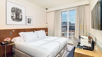 Une chambre d’hôtel avec un grand lit, un bureau avec un ordinateur, une chaise, une table de chevet avec une lampe et une fenêtre avec des rideaux.