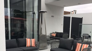 An outdoor seating area with two sofas and a coffee table, a metal chair, and a small table.