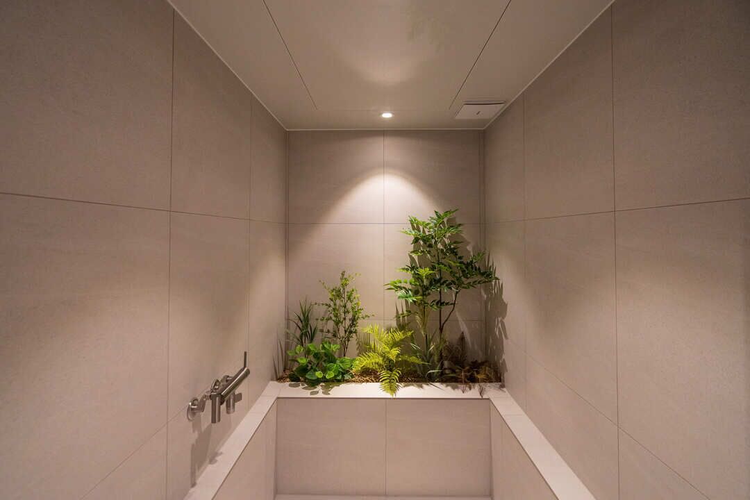Un baño moderno con ducha empotrada, un pequeño arreglo de plantas y un perchero para toallas.