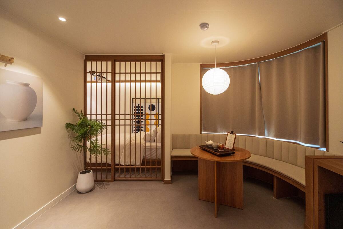 A modern interior with a seating area, a wooden partition, a potted plant, and a table with a tray.