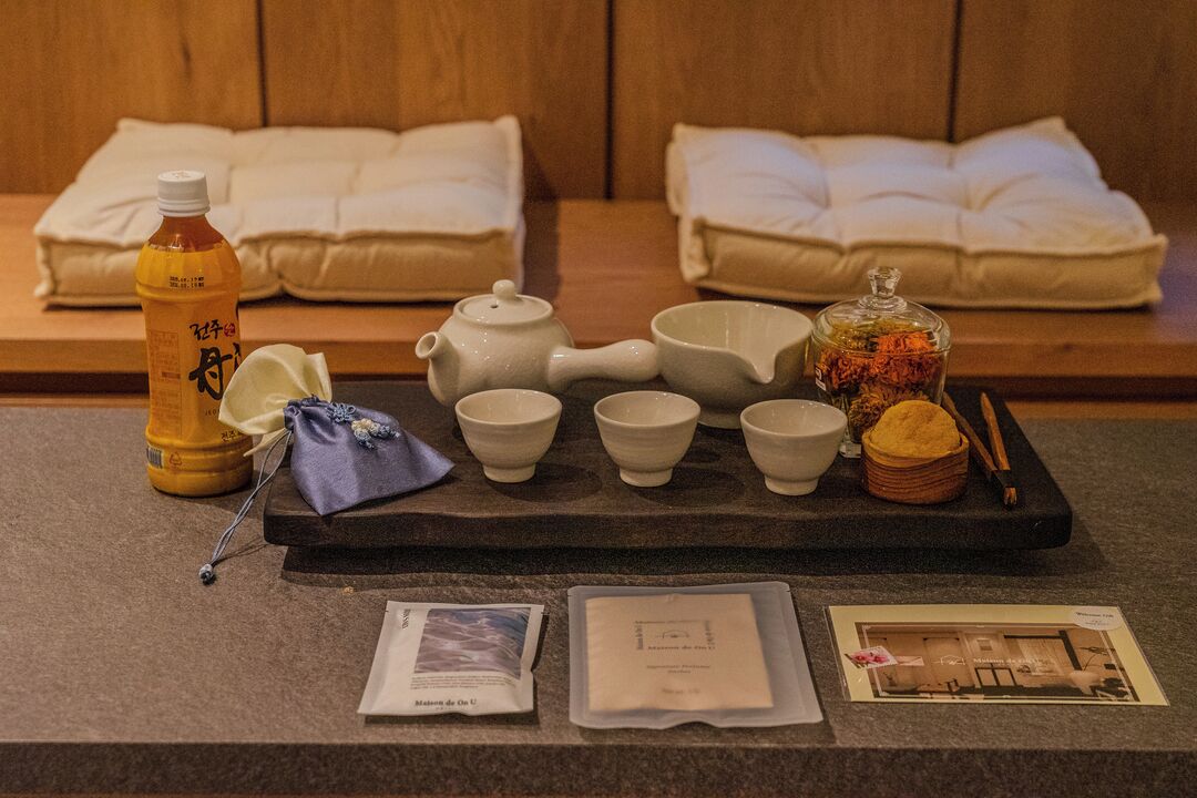 A tea set with cups, a teapot, and a bottle on a tray, along with a small bag and informational pamphlets.