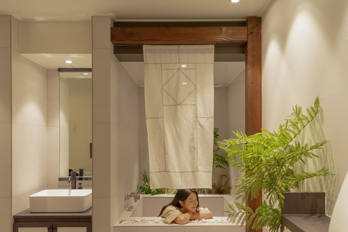 A modern bathroom with a large sink, mirror, and a shower curtain.