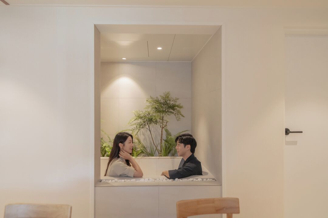 Una habitación con una pared blanca, una silla de madera y una planta.