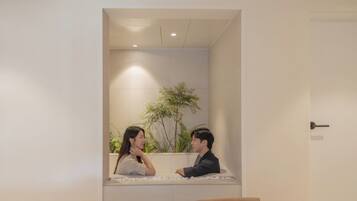 Una habitación con una pared blanca, una silla de madera y una planta.