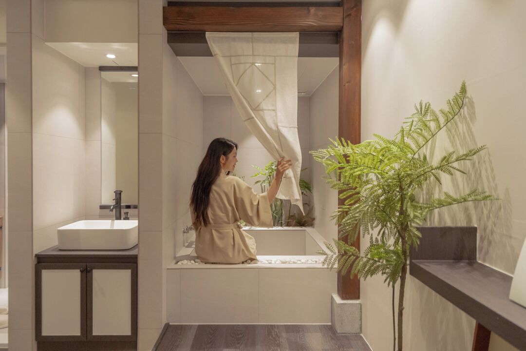 A modern bathroom with a bathtub, a sink, and a potted plant.