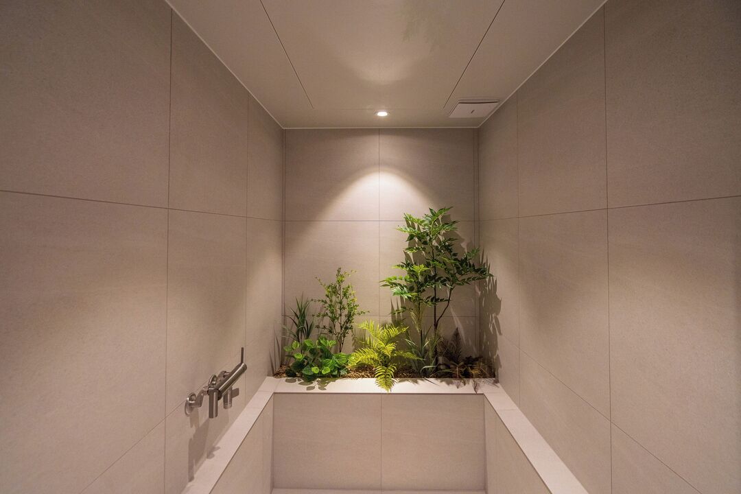A modern bathroom with a recessed shower area, a built-in plant shelf, and a towel rack.