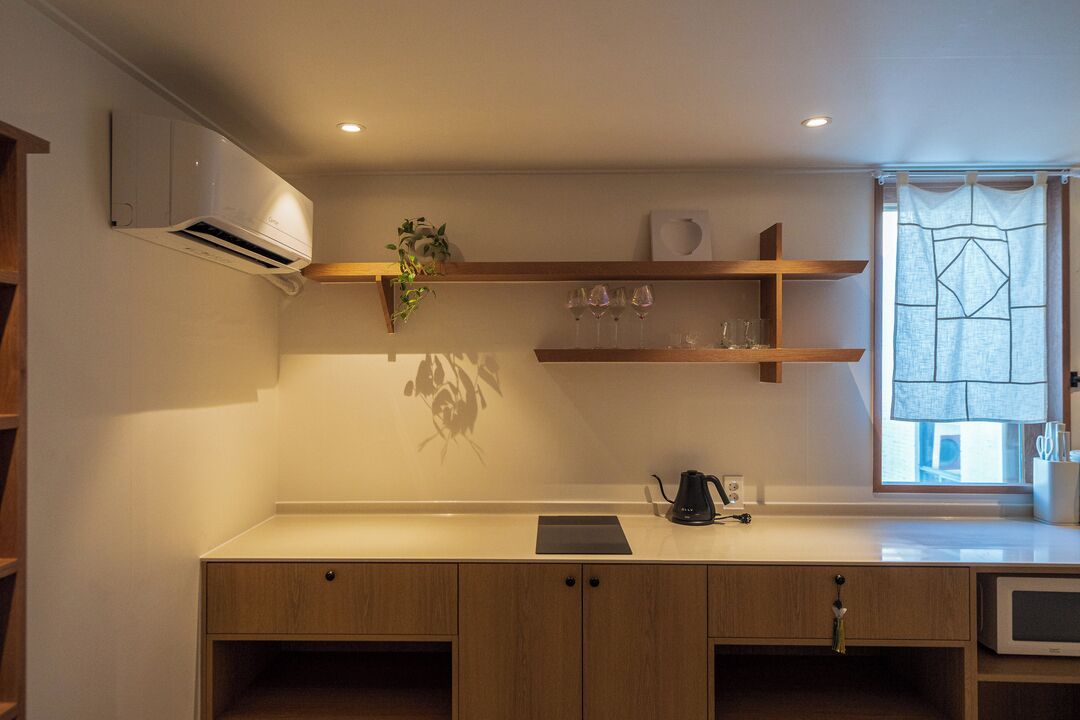 A kitchen with wooden cabinets, a countertop, a coffee maker, and a window with a curtain.