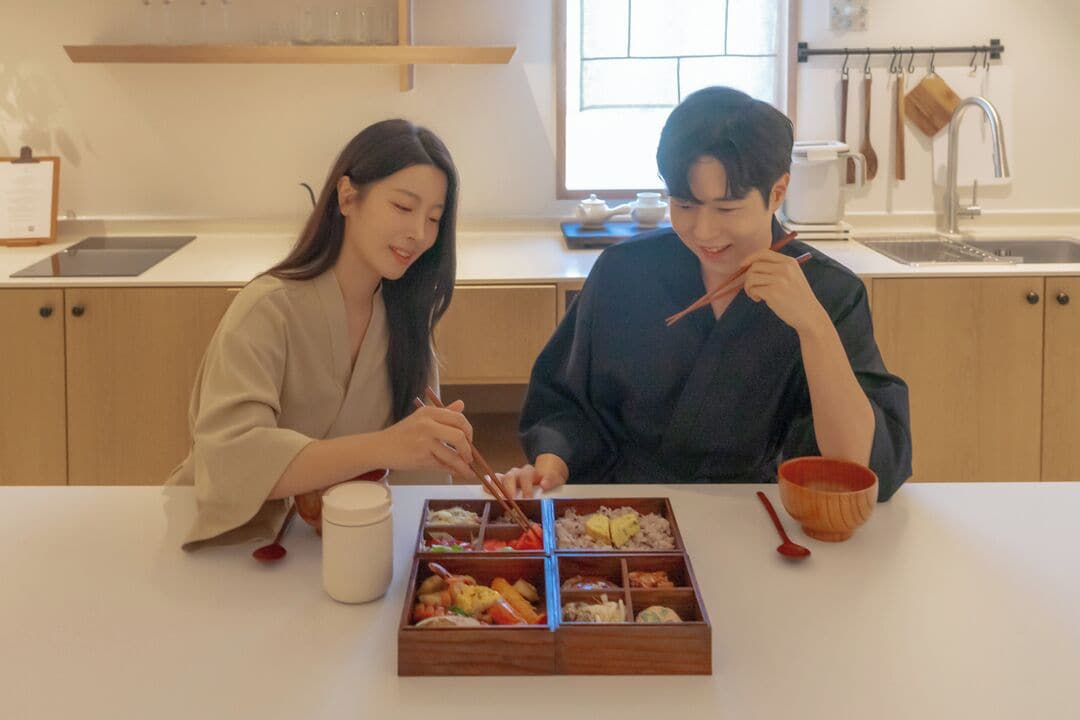 A dining table with a meal, a cup, and chopsticks.