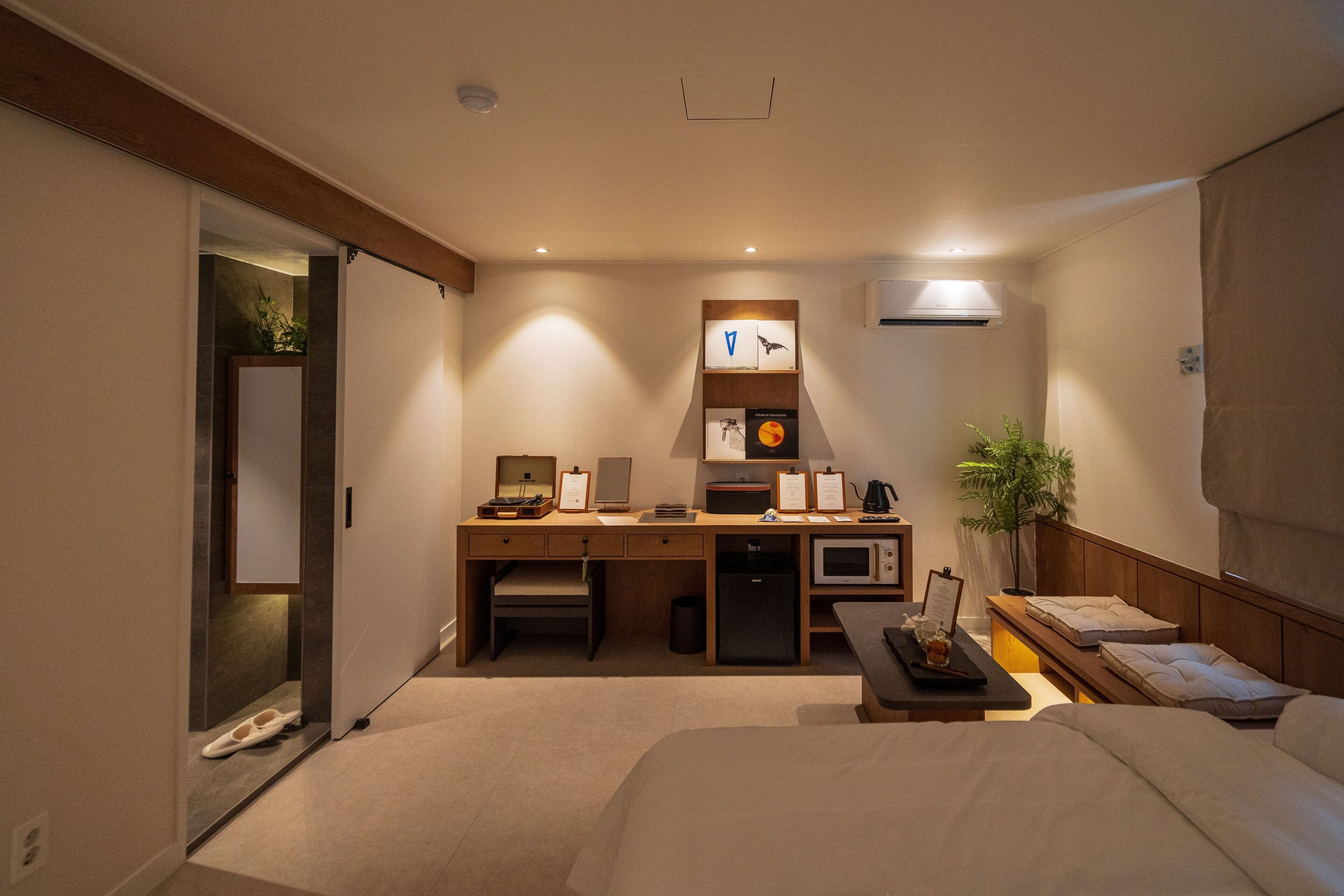A hotel room with a bed, desk, microwave, and a small seating area.