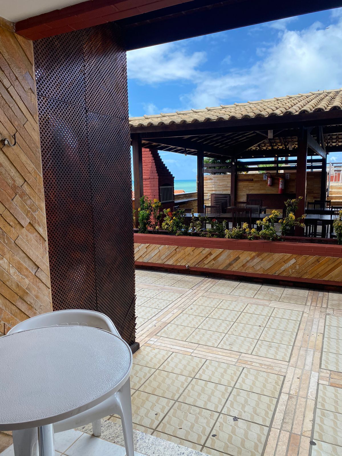 A covered outdoor area with a tiled floor, a table, and chairs.