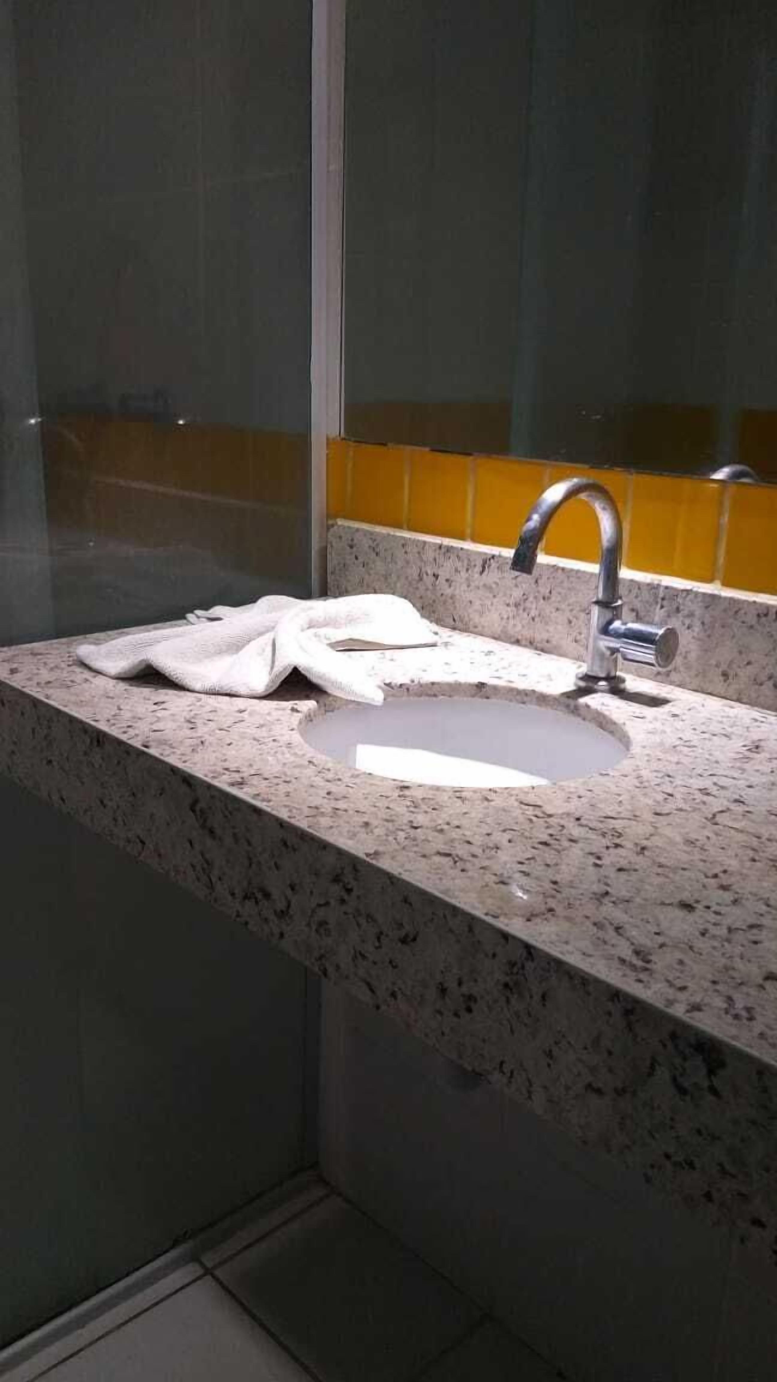 A bathroom with a granite countertop, a sink, and a mirror.