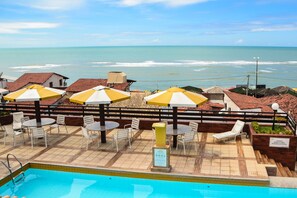 Una piscina al aire libre, sombrillas, sillones reclinables de piscina