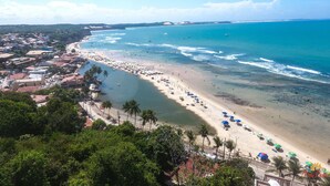 A coastal town with a beach, clear blue waters, and a mix of residential and commercial buildings. - Flat Pipa Oceano (Tibau do Sul)