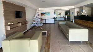 A modern living room with a flat-screen TV, a Christmas tree, and a reception desk. - Flat Pipa Oceano (Tibau do Sul)