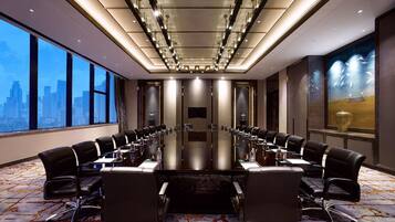 A conference room with a long table, black chairs, and a cityscape view.