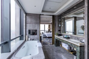 Un baño de hotel moderno con una bañera grande, un lavamanos doble y un espejo amplio.