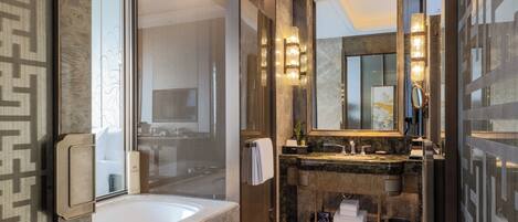 A modern bathroom with a large bathtub, a vanity with a mirror, and a shower area.
