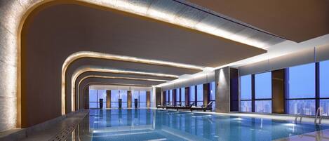 Una piscina interior moderna con vistas a la ciudad, con un diseño elegante y abundante luz natural.