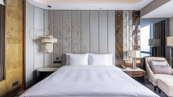 A hotel room with a large bed, a nightstand, a chair, and a decorative wall panel.