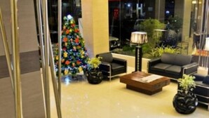 Een moderne lobby met een kerstboom, zachte zitplaatsen en een glazen wand met uitzicht op de stad.