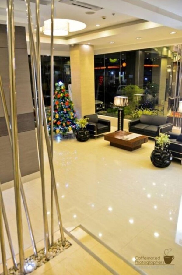 Un vestíbulo moderno con un árbol de Navidad, asientos cómodos y un muro de cristal que ofrece vistas de la ciudad.