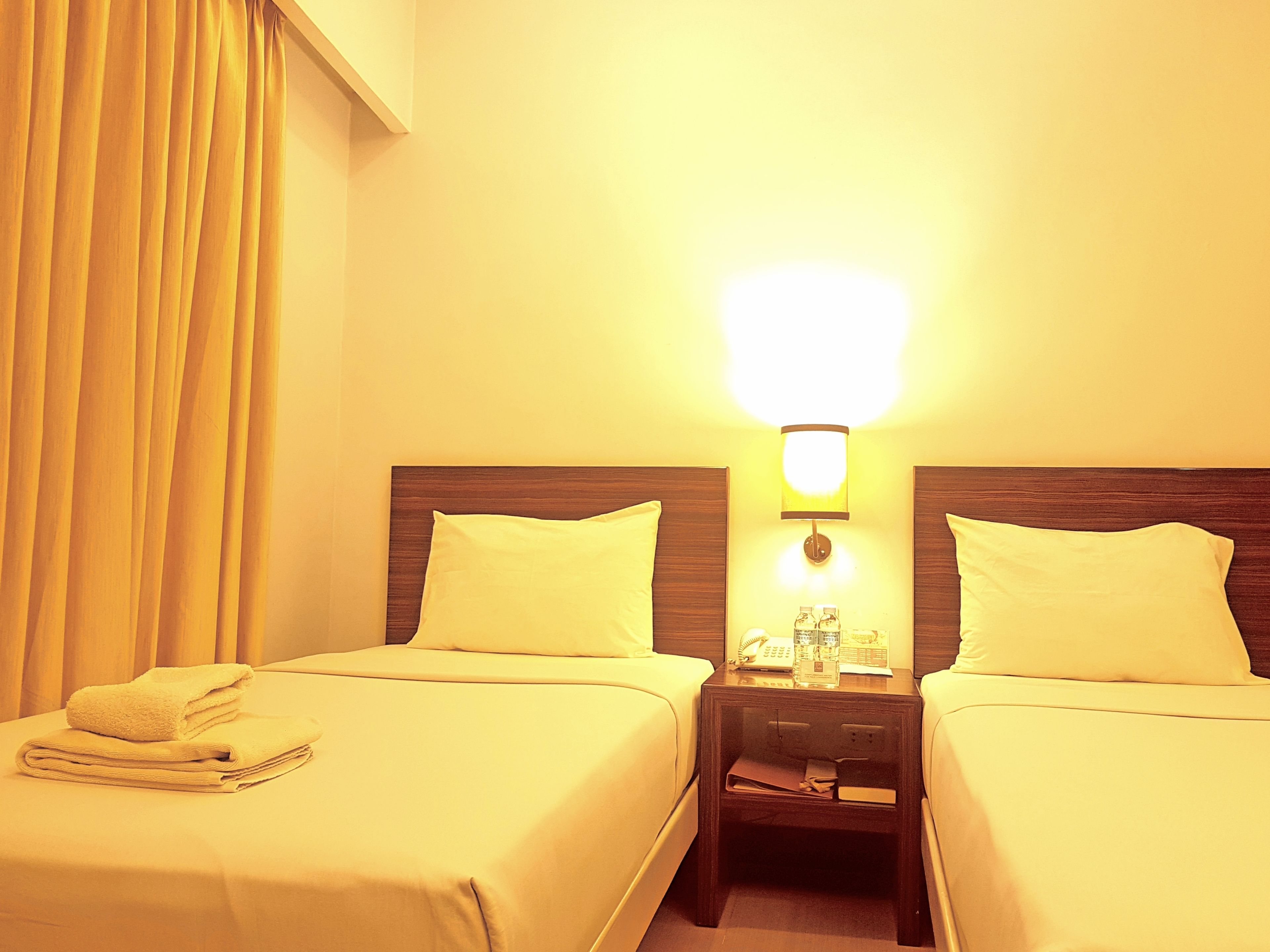 Une chambre d’hôtel avec deux lits, une table de chevet avec une lampe et un téléphone.