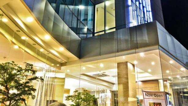 Een modern gebouw met een glazen gevel en verlichte signage.