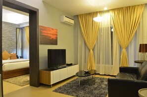 A modern hotel room with a bed, TV, and a seating area with a table and sofa. - D' Hotel and Suites (Dipolog)